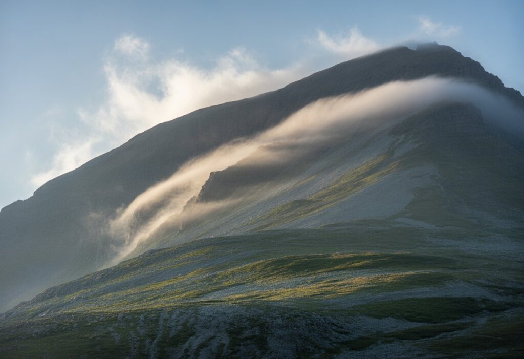 Mountain ridge with wind blowing upward along the slope, showing rising air currents on the windward side.