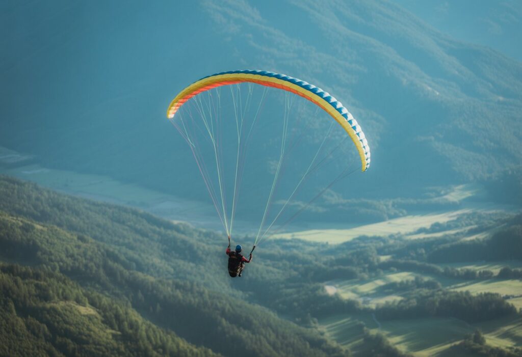 A paraglider performing wing overs in the sky above green mountains and valleys.